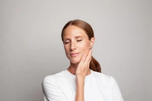 Vrouw met een gezonde, stevige huid raakt haar wang aan